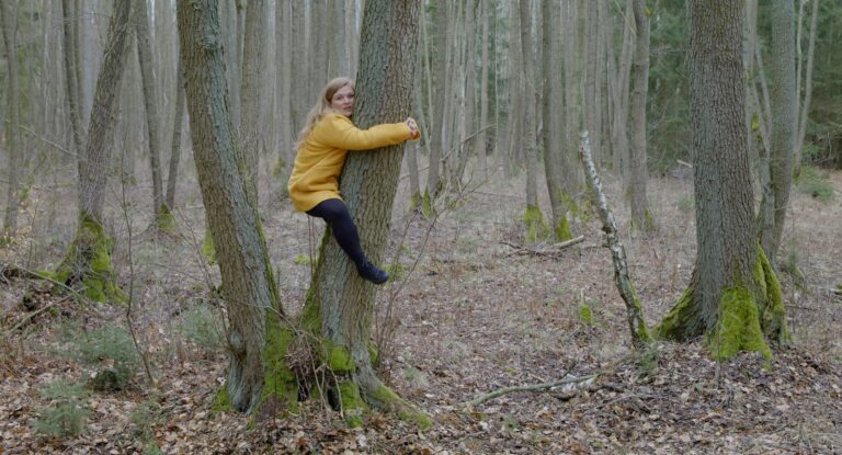 eine Schauspielerin ist an einen Baumstamm geklammert in zwei Metern Höhe