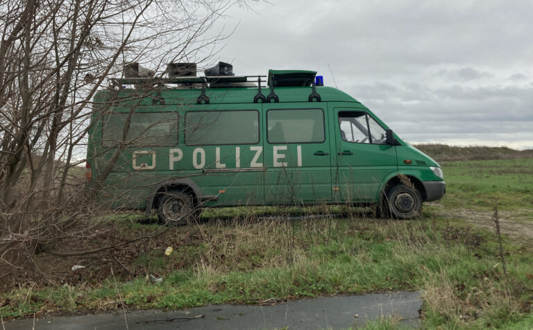 Ein grüner Polizei-Bus steht auf grüner Wiese